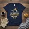 T-shirt with "That Sounds Like My Husband's Problem" quote, featuring a cartoon man and a frying pan graphic