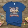 Text "That's My Bro I'm Just Here For The Snack Bar" with baseball and bats graphic on a blue t-shirt