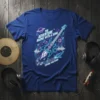 The Adventure Begins With A Song Explore Your Sound text and rocket guitar graphic on a blue t-shirt