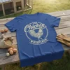 The Chicken Whisperer t-shirt design featuring a detailed rooster illustration and vintage circular text