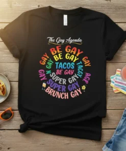 Black t-shirt with colorful text "The Gay Agenda BE GAY BE GAY TACOS BE GAY SUPER GAY SUPER GAY BRUNCH