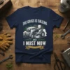 The Grass Is Calling And I Must Mow quote on a navy t-shirt with a graphic of a riding lawn