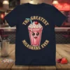The Greatest Milkshake Ever text above a cute cartoon milkshake with sprinkles and a cherry, on a navy t-shirt