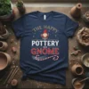 The Happy Pottery Gnome Christmas T-Shirt with a festive gnome holding a gift and a pottery wheel, surrounded by holiday