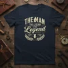 The Man The Legend The Legend quote on a navy blue t-shirt with distressed cream typography and laurel wreath graphic