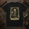 The Reader t-shirt design with a skeleton reading a book, tarot card style, moon, butterflies, and floral accents