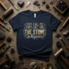 Navy t-shirt with gold and white text that reads "They Call Me They Call The The Stone Whisperer!" featuring crystal