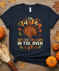 The Turkey Ain't The Only Thing IN THE OVEN graphic tee with a cute turkey and baby footprints, perfect for