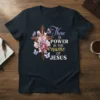 Christian t-shirt with the quote "There is POWER in the name of JESUS" next to a wooden cross with flowers