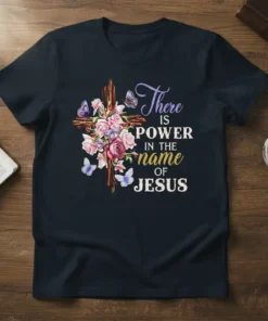 Christian t-shirt with the quote "There is POWER in the name of JESUS" next to a wooden cross with flowers