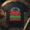 T-shirt design with bold text "THESE GUNS NO LONGER IDENTIFY AS GUNS THEY SELF-IDENTIFY AS HANDHELD WIRELESS PEACEKEEPING DEVICES YOU