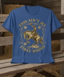 This Ain't My First Rodeo text with a cowboy riding a bucking horse graphic on a blue t-shirt
