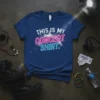 Blue t-shirt with "THIS IS MY CONCERT SHIRT." text in neon pink and blue, featuring a crowd graphic and spotlights