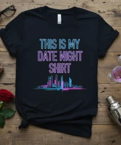 Black t-shirt with neon blue and pink text reading "THIS IS MY DATE NIGHT SHIRT" above a neon cityscape graphic