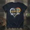 T-shirt with text "THIS PASTOR Loves You" inside a heart with rainbow and transgender pride flag colors and a silver