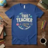 This Teacher Is Glowing text with school icons on a blue t-shirt
