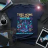 Tired Moms Book Club shirt design with neon city skyline, books, coffee, and quote "Running on Coffee, Chaos and Chapters"