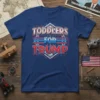 Toddlers For Trump text design with red, white, and blue stars and stripes graphic on a blue t-shirt