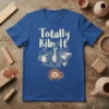 Totally Kiln It text with pottery graphics including a kiln, mugs, and bowls on a blue t-shirt