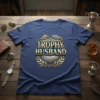 Trophy Husband t-shirt design featuring bold gold text, a shield, gears, and laurel leaves on a navy blue shirt