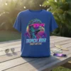 TROPICAL RIDER SUNSET SURF CLUB text on a blue t-shirt with a retro bird wearing sunglasses and palm trees