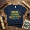 Navy t-shirt with gold text quoting "Trouble. Good Trouble. Necessary Trouble. John Lewis" in a bold, artistic design