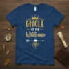 UNCLE OF THE Wild one text with a gold crown and compass graphic on a navy blue t-shirt