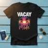 Vacay Mode text above a vibrant tropical sunset with palm trees, birds, and sparkling accents on a black t-shirt