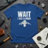 Wait I See A Rock T-Shirt featuring bold white text and a geometric rock graphic with mountains