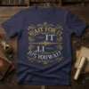 Navy t-shirt with gold and silver ornate text design that reads "WAIT FOR IT - A. Burr IT LI JUS