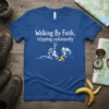 Royal blue t-shirt with white text "Walking By Faith, tripping constantly" and a graphic of two stick figures, one tripping