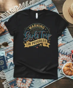 WARNING Girls Trip IN PROGRESS text graphic on a black t-shirt, featuring retro-style typography and travel icons like airplanes and