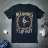 Gymnast performing a handstand on a t-shirt with text "Warning I Might Flip Out" and decorative border