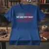 Blue t-shirt with distressed American flag graphic and "WE ARE NOT OKAY" text in white