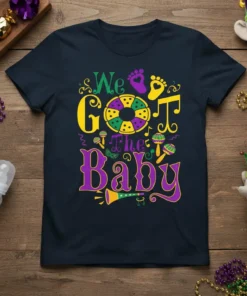 We Got The Baby text with Mardi Gras colors and baby-themed graphics on a navy t-shirt