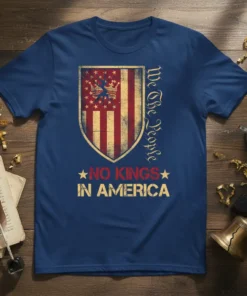 We The People NO KINGS IN AMERICA text with distressed US flag shield graphic on navy t-shirt