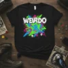 Black t-shirt with "WEIRDO" in white bold font over a chaotic splatter of neon pink, blue, and green paint, with