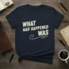 Navy blue t-shirt with white text reading "WHAT HAD HAPPENED WAS" in a retro font, with a decorative swirl below