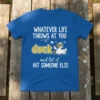WHATEVER LIFE THROWS AT YOU duck and let it HIT SOMEONE ELSE quote on a blue t-shirt with a cartoon
