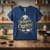 Blue t-shirt with "What's Cookin'" text in yellow, chef hat, frying pan with egg, and cooking pot graphic