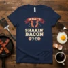 What's Shakin' Bacon text design with dancing bacon strips on a navy t-shirt