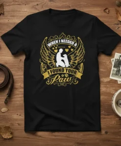 Black t-shirt with "When I Needed A I Found Your Paw" text and a silhouette of a person hugging a
