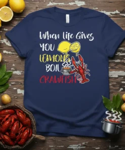 Navy blue t-shirt with white and yellow text reading "When life Gives YOU LEMONS BOIL" and red text "CRAWFISH," featuring