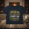 Navy t-shirt with gold and white text that reads "WHEW THAT WAS CLOSE I ALMOST HAD TO SOCIALIZE" in a