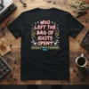 Black t-shirt with white and red text reading "WHO LEFT THE BAG OF IDIOTS OPEN? SERIOUSLY! THEY'RE EVERYWHERE!" and quirky