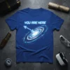 Blue t-shirt with "YOU ARE HERE" text and a vibrant spiral galaxy graphic pointing to its center