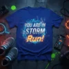 Blue t-shirt with "YOU ARE IN STORM Run!" text in distressed silver and bright orange, surrounded by a geometric blue