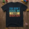 You Don't Scare Me I Have Seven Kids quote on a black t-shirt, featuring distressed blue, teal, and orange lettering