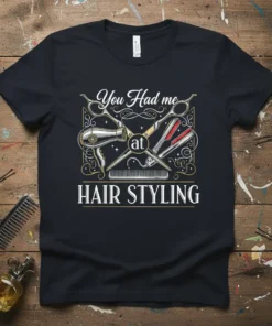 Black t-shirt with "You Had me at HAIR STYLING" text and graphics of scissors, comb, hair dryer, and razors