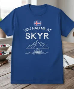 Blue t-shirt with "You Had Me At Skyr" text, Icelandic flag, mountains, and Viking ship graphic